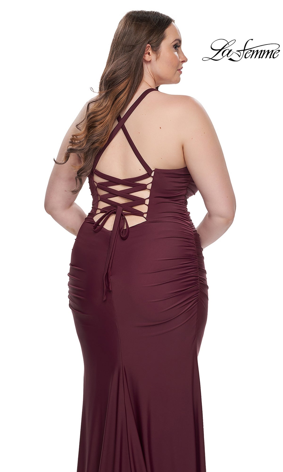 A woman models the La Femme Plus-Size Lace-Up Long Prom Dress 32195 in maroon, featuring a lace-up back and ruched sides, standing against a plain white background.